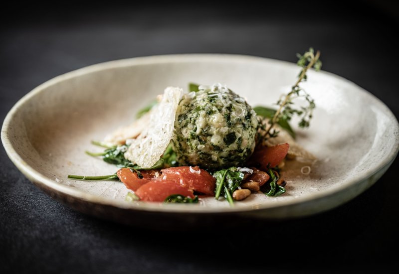 Spinatknödel mit Tomatenfilets und gerösteten Pinienkernen